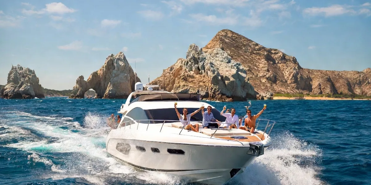 White motor yacht cruising past El Arco at Cabo San Lucas with guests on the bow deck
