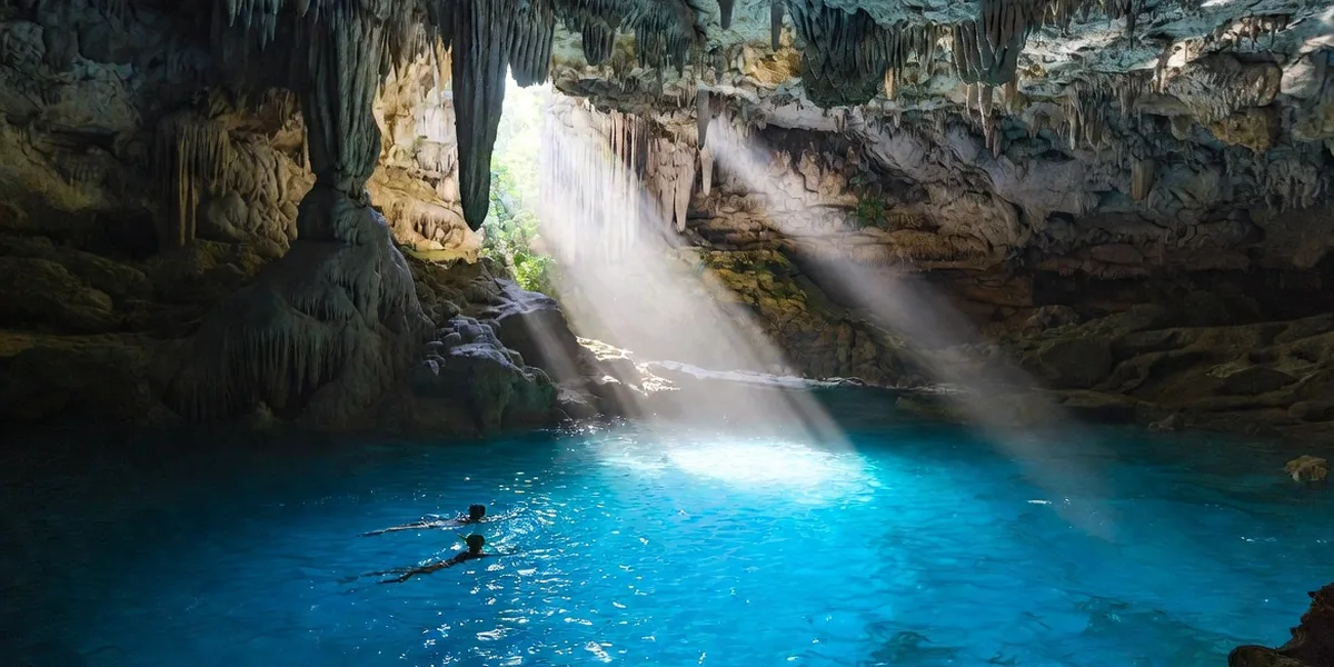 Snorkelers floating in the glowing blue cavern pool of Cenote Dos Ojos near Tulum