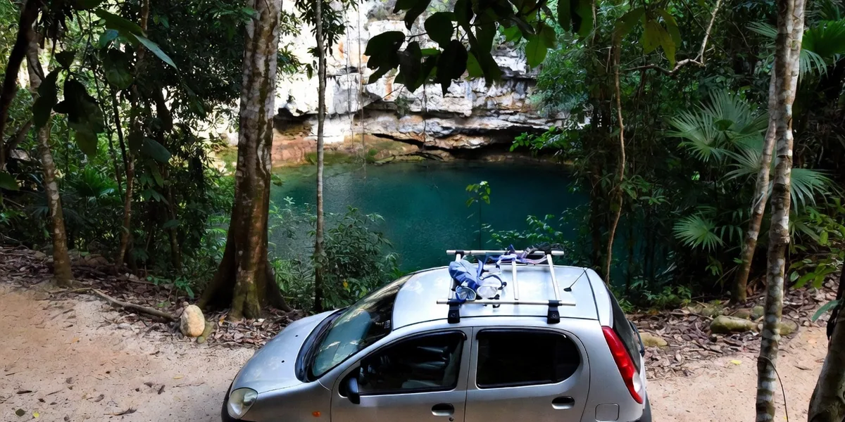 Rental car parked at a jungle cenote entrance with snorkel gear ready — the DIY cenote day trip