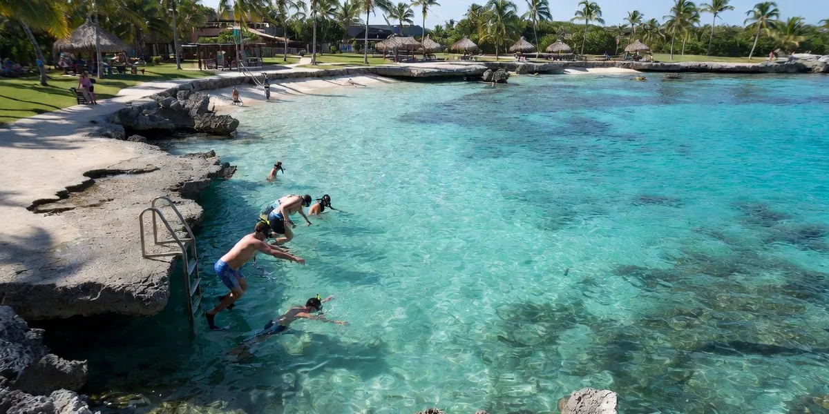 Snorkelers entering the clear water at Chankanaab's rocky shoreline park, Cozumel