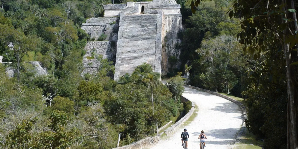 The Nohoch Mul pyramid rising from the jungle at Cobá with cyclists on the forest path