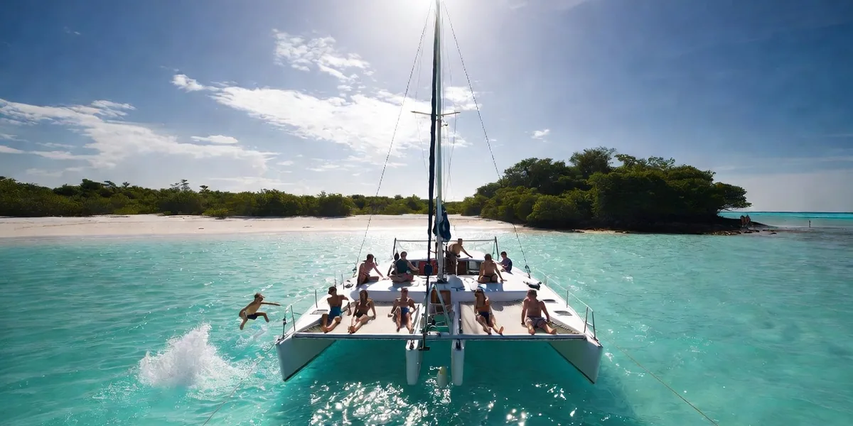 Sailing catamaran anchored in turquoise water off Playa Norte, Isla Mujeres, with snorkelers nearby