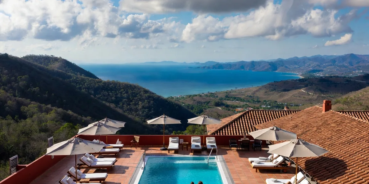 Rooftop pool deck in Zona Romántica looking over red-tile roofs to Banderas Bay, Puerto Vallarta