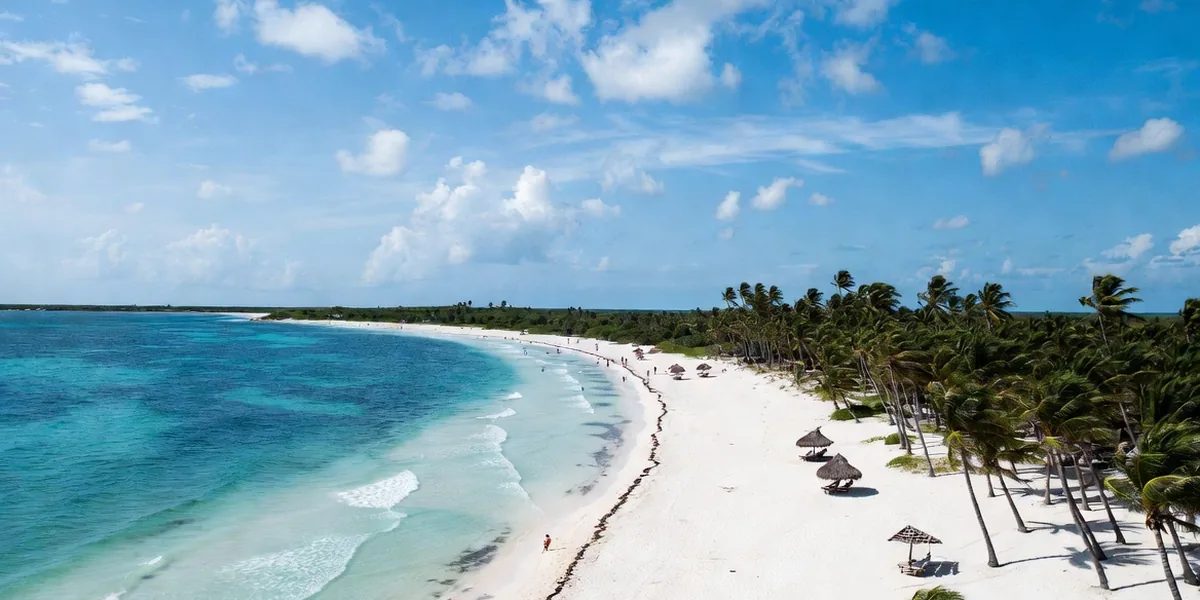 Wide calm bay, palms and rustic palapas at Xpu-Há beach on the Riviera Maya